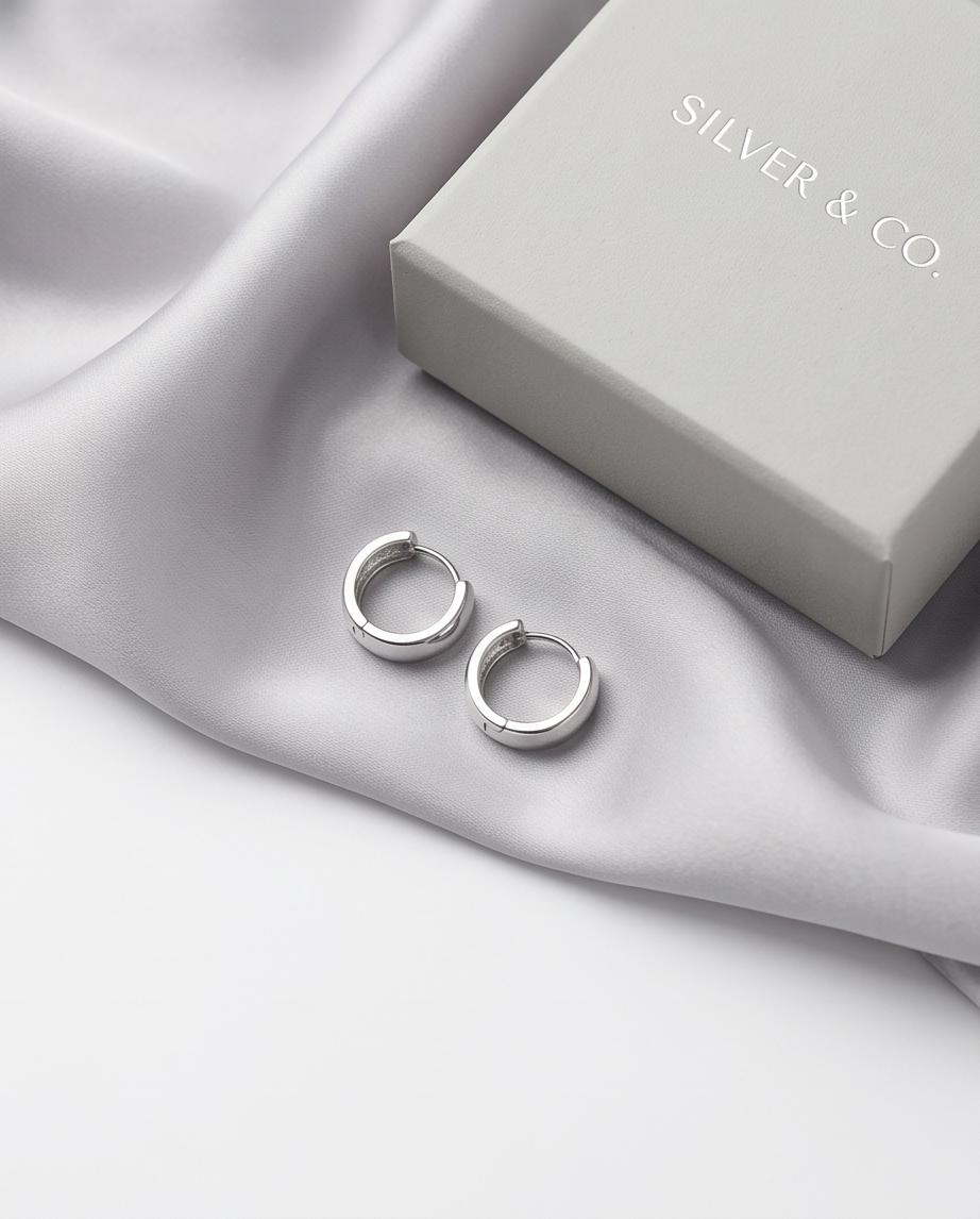 Minimalist silver‑tone hoop earrings with a smooth, polished finish