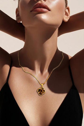 A gold‑tone clover pendant necklace with warm tortoiseshell detail