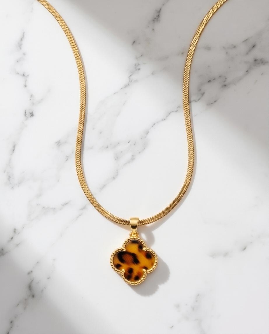 A gold‑tone clover pendant necklace with warm tortoiseshell detail
